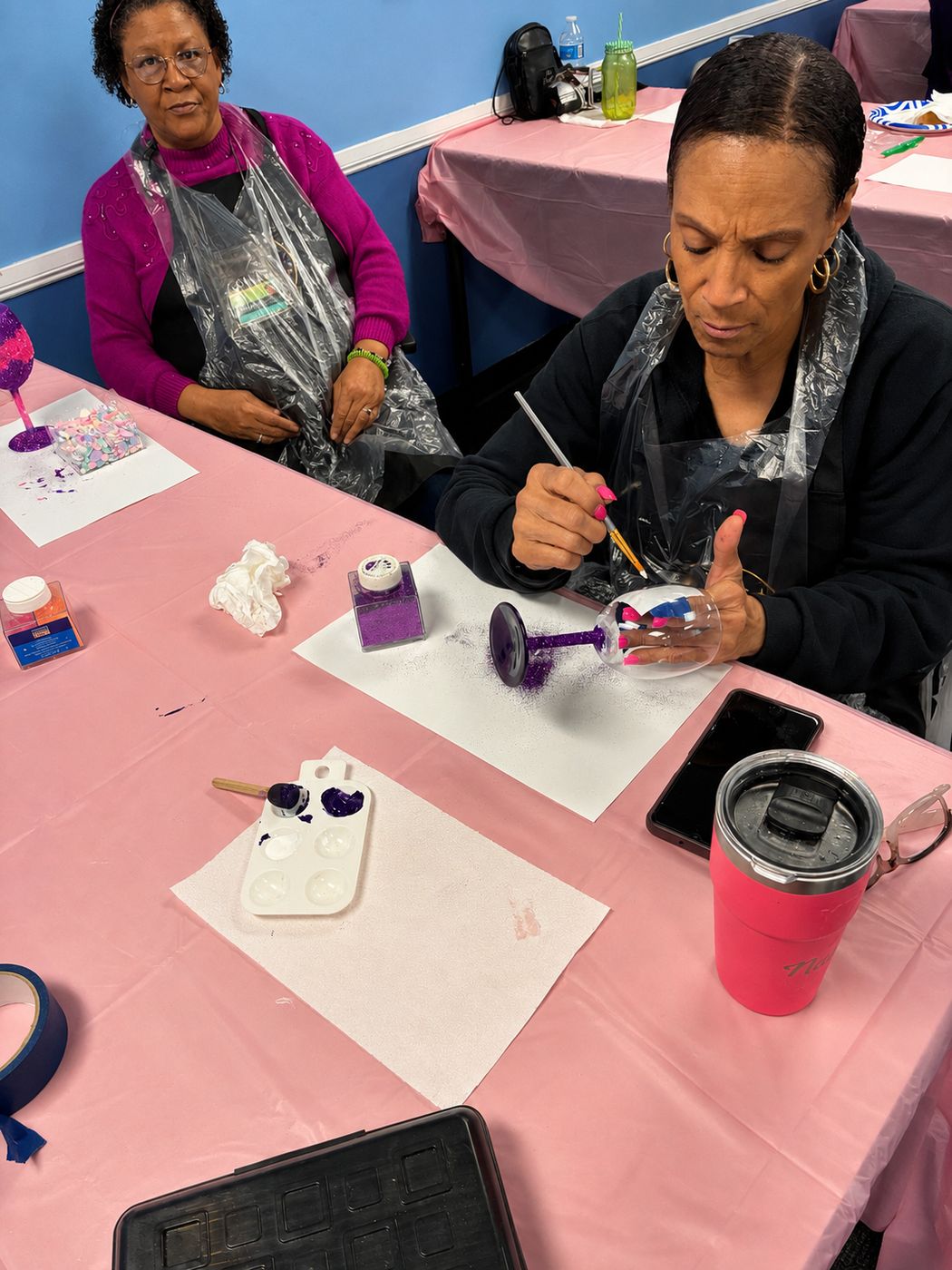 Two women painting wine glasses
