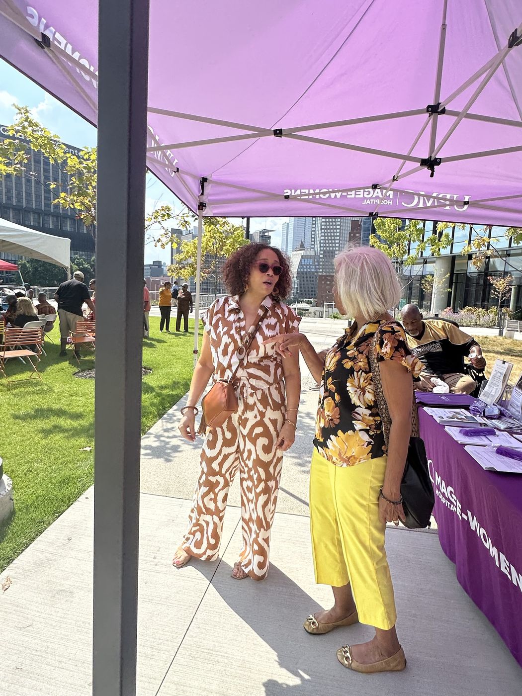 A health partner talks with a resident at a resource table during an outdoor community event