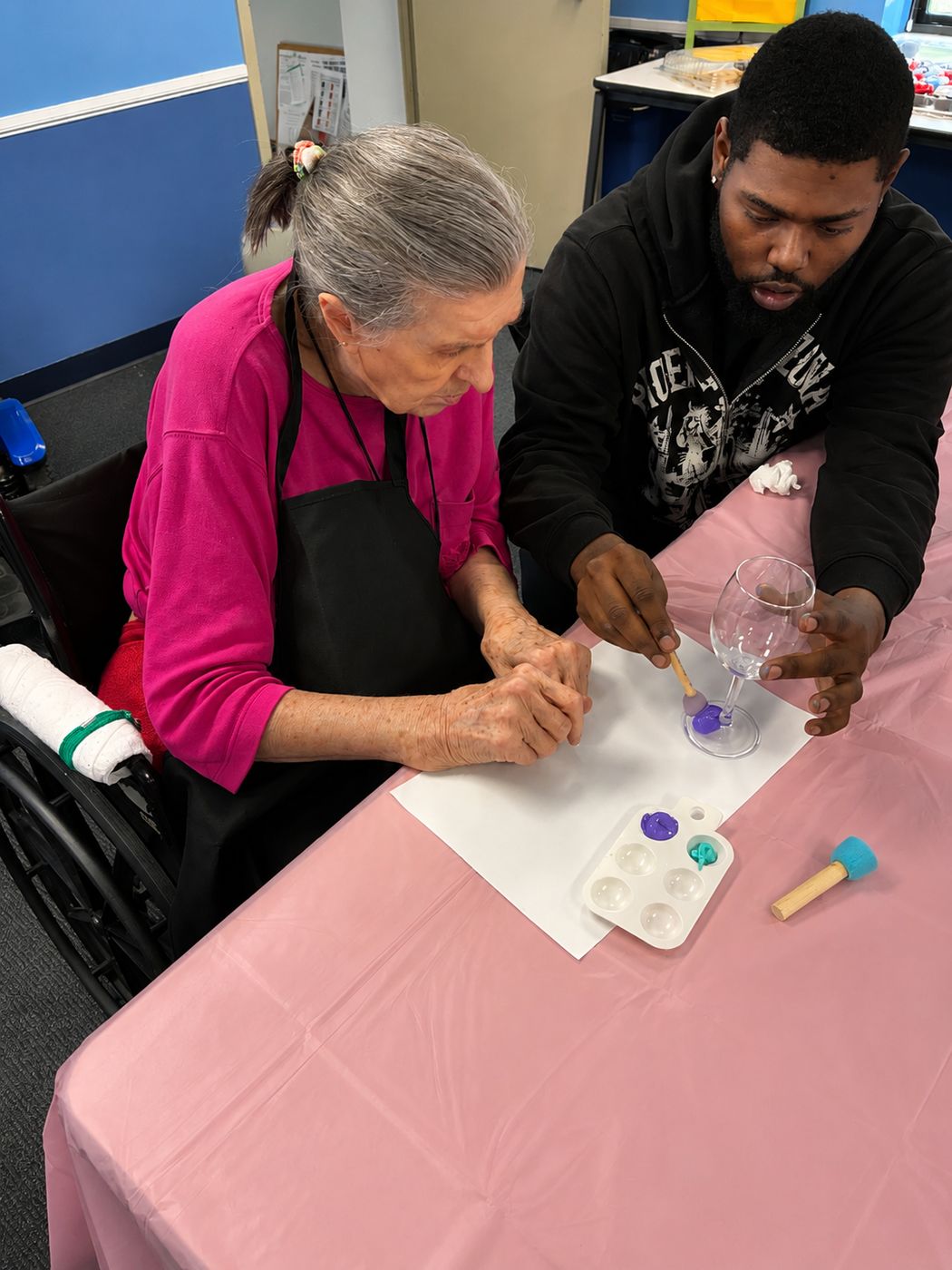 A volunteer helps an older woman paint