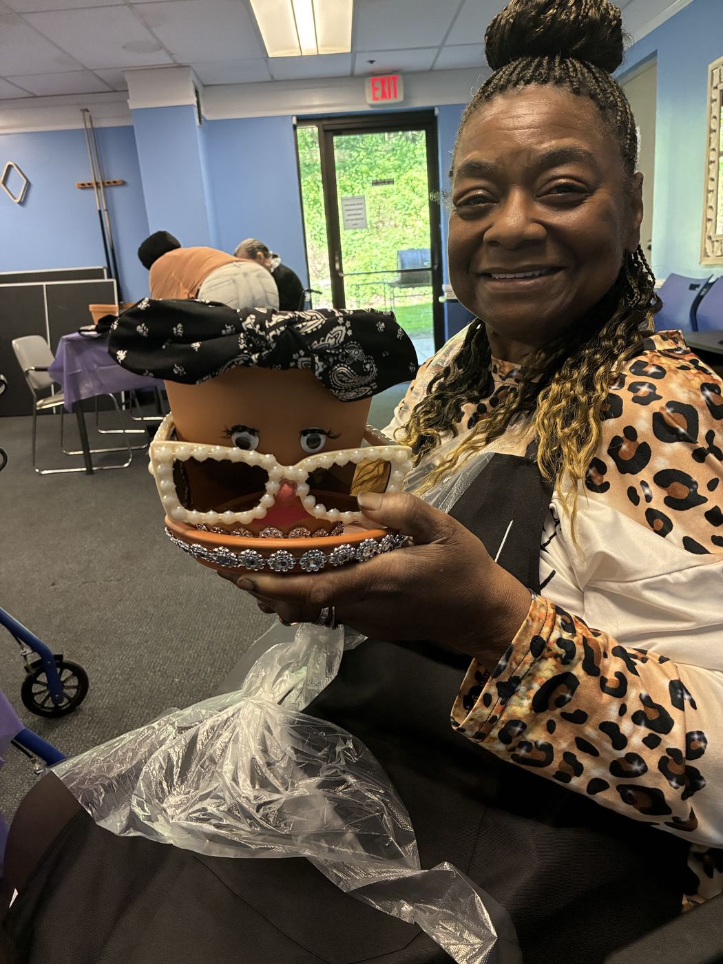 A smiling senior holds up her decorated flower pot