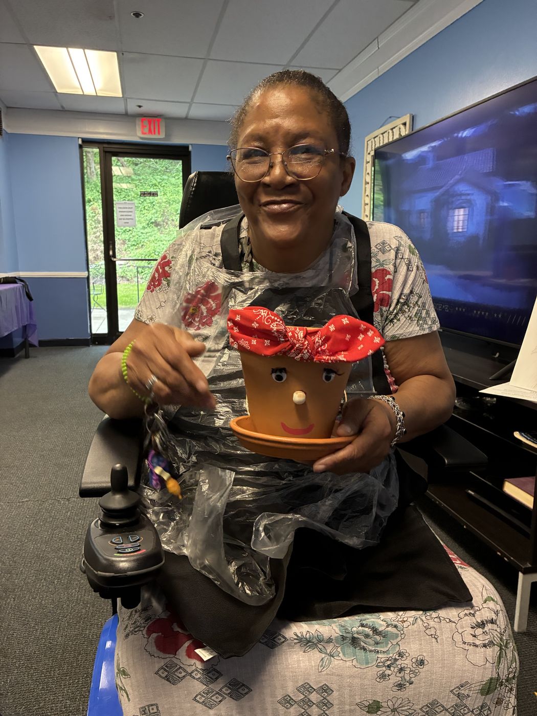 A senior smiles while holding the flower pot she decorated