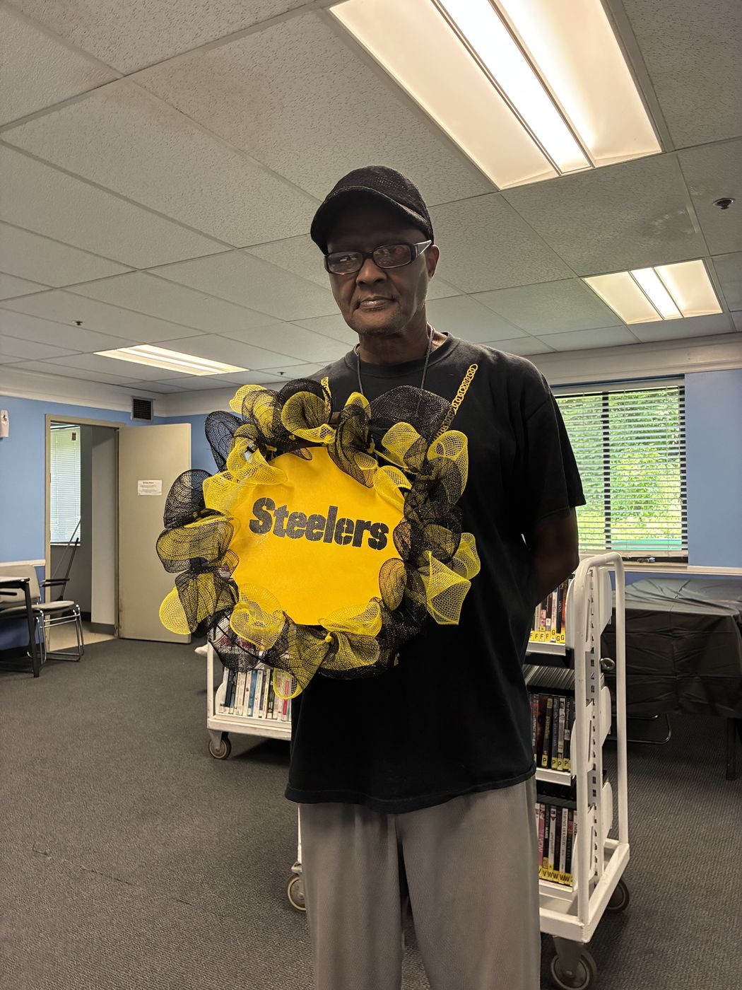 A senior holds a black and gold wreath he made